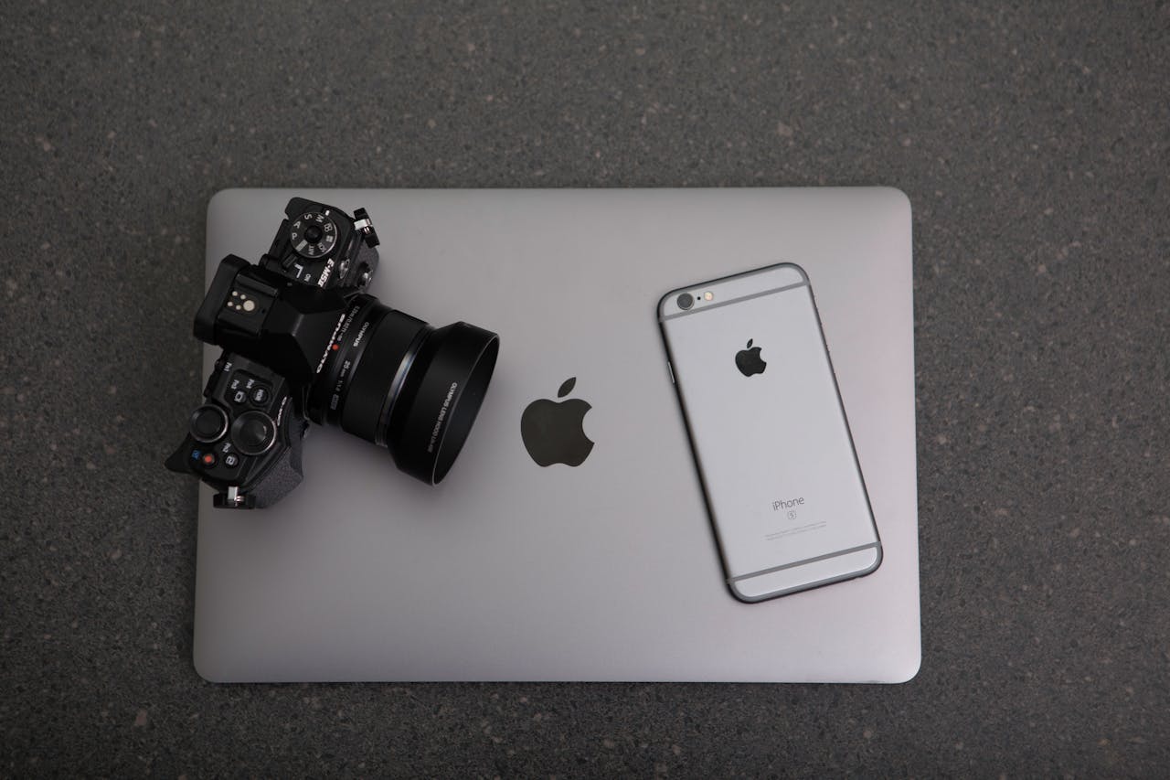 services-03 High-angle shot of DSLR camera, MacBook, and iPhone on textured surface, showcasing modern technology essentials.